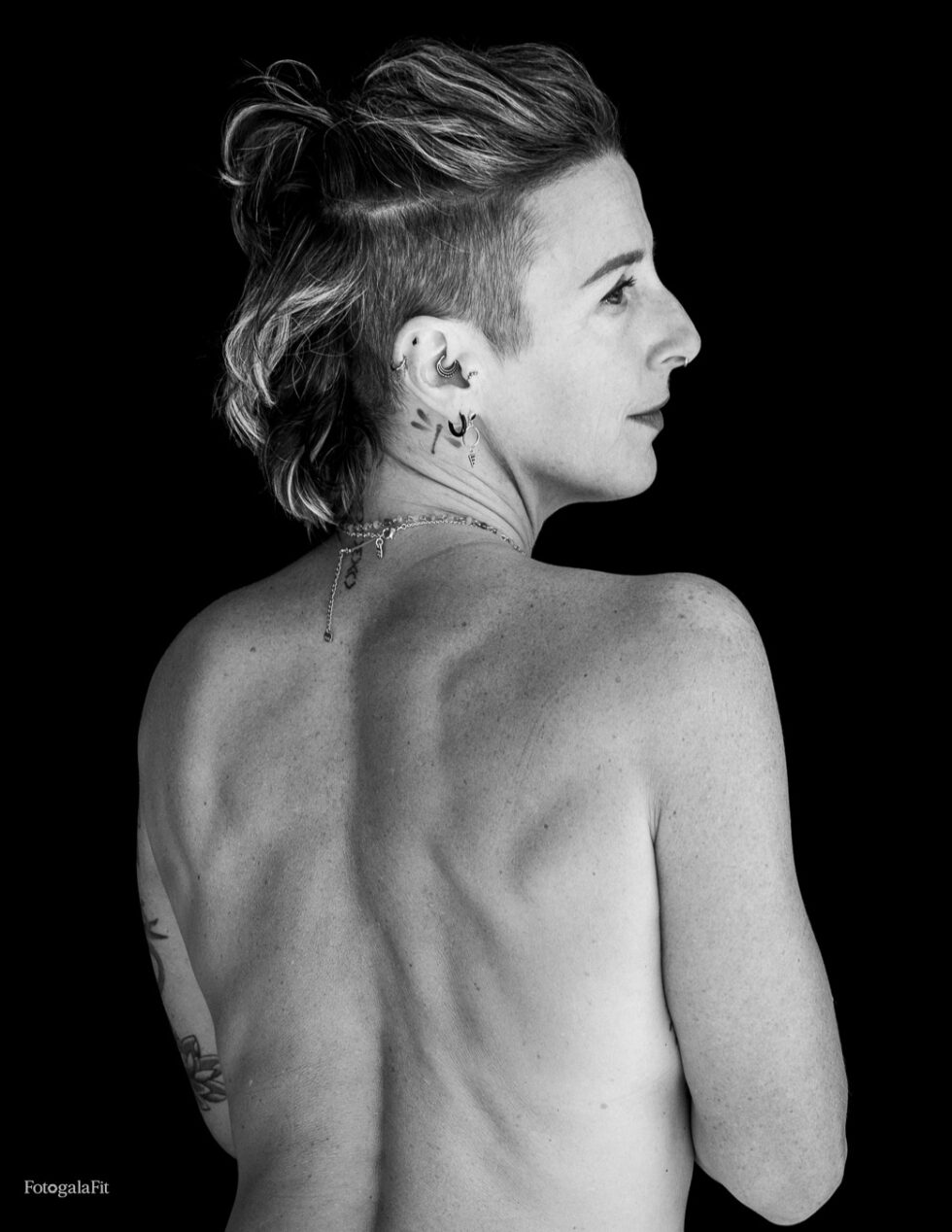 Retrato de Mathilde en blanco y negro, de espaldas y con el rostro girado de perfil sobre el hombro, frente a un fondo negro.
